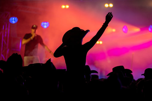 woman in cowboy hat raised above crowd at country concert